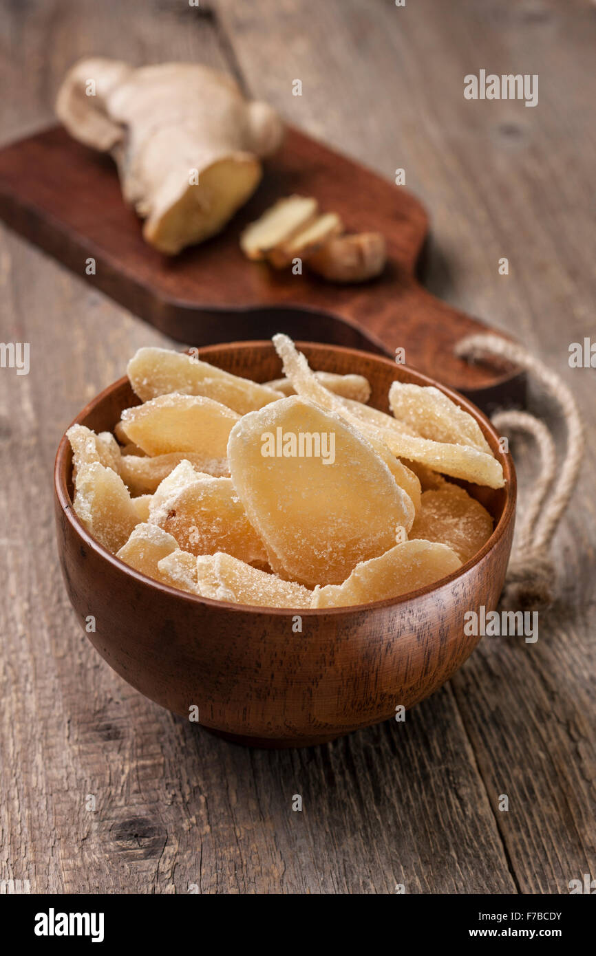 Gingembre Confit dans un bol en bois, de gingembre frais sur une planche à découper dans un style rustique Banque D'Images