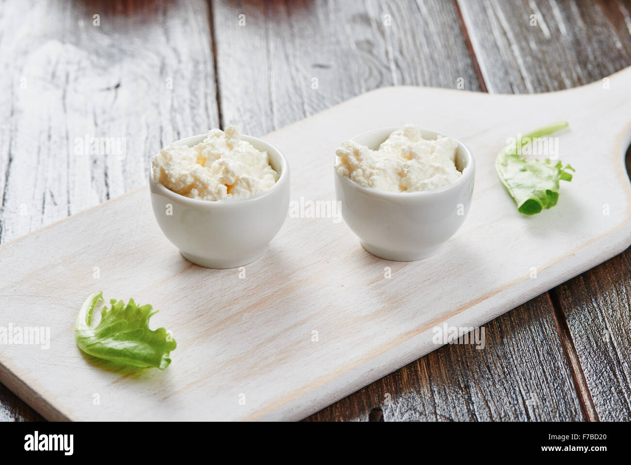 Le fromage cottage dans deux bols sur la table en bois blanc et salade Banque D'Images