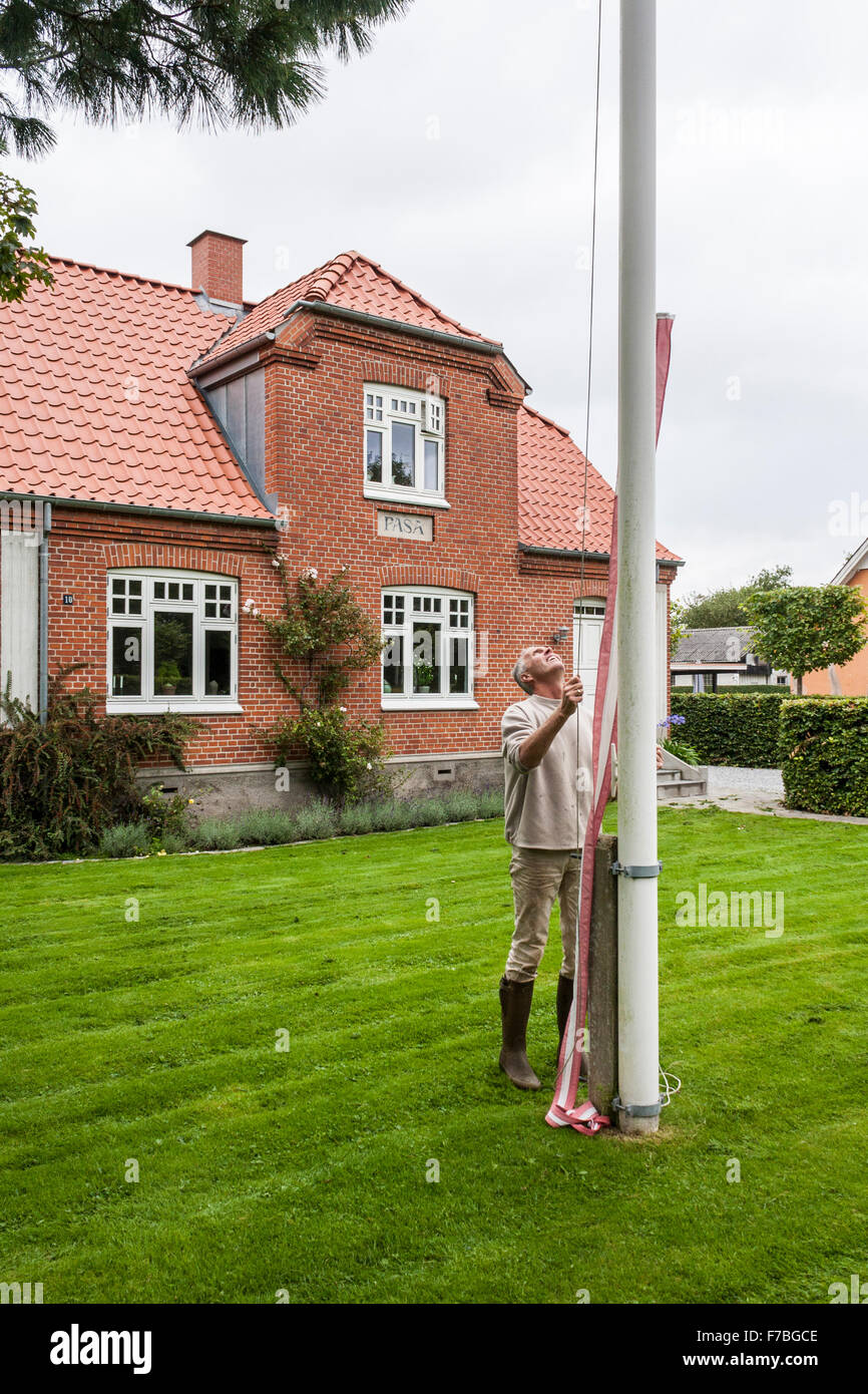 L'homme drapeau national de sensibilisation du Danemark à l'extérieur de maison à campagne danoise. Banque D'Images