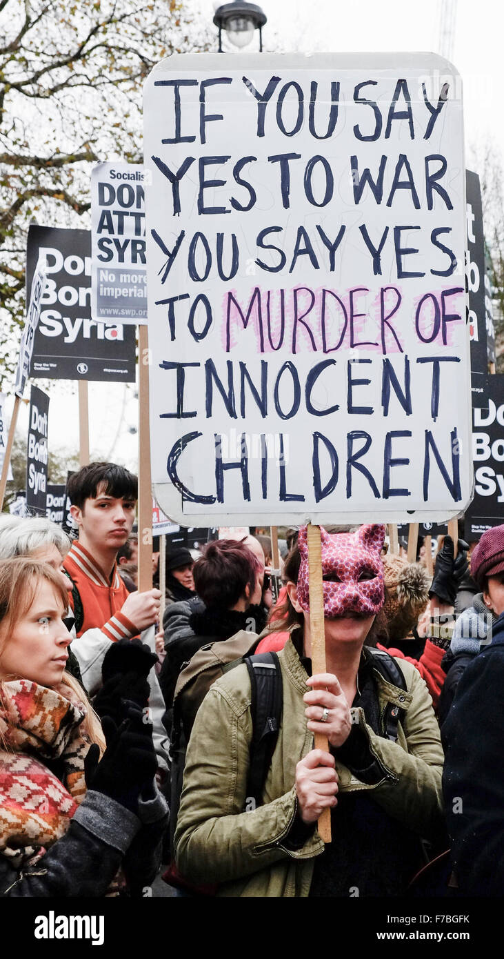 Londres, Royaume-Uni, le 28 novembre, 2015. Un manifestant masqué nous tend un placard pour protester contre la proposition du gouvernement britannique de bombardement de commencer la Syrie. Credit : Gordon 1928/Alamy Live News Banque D'Images