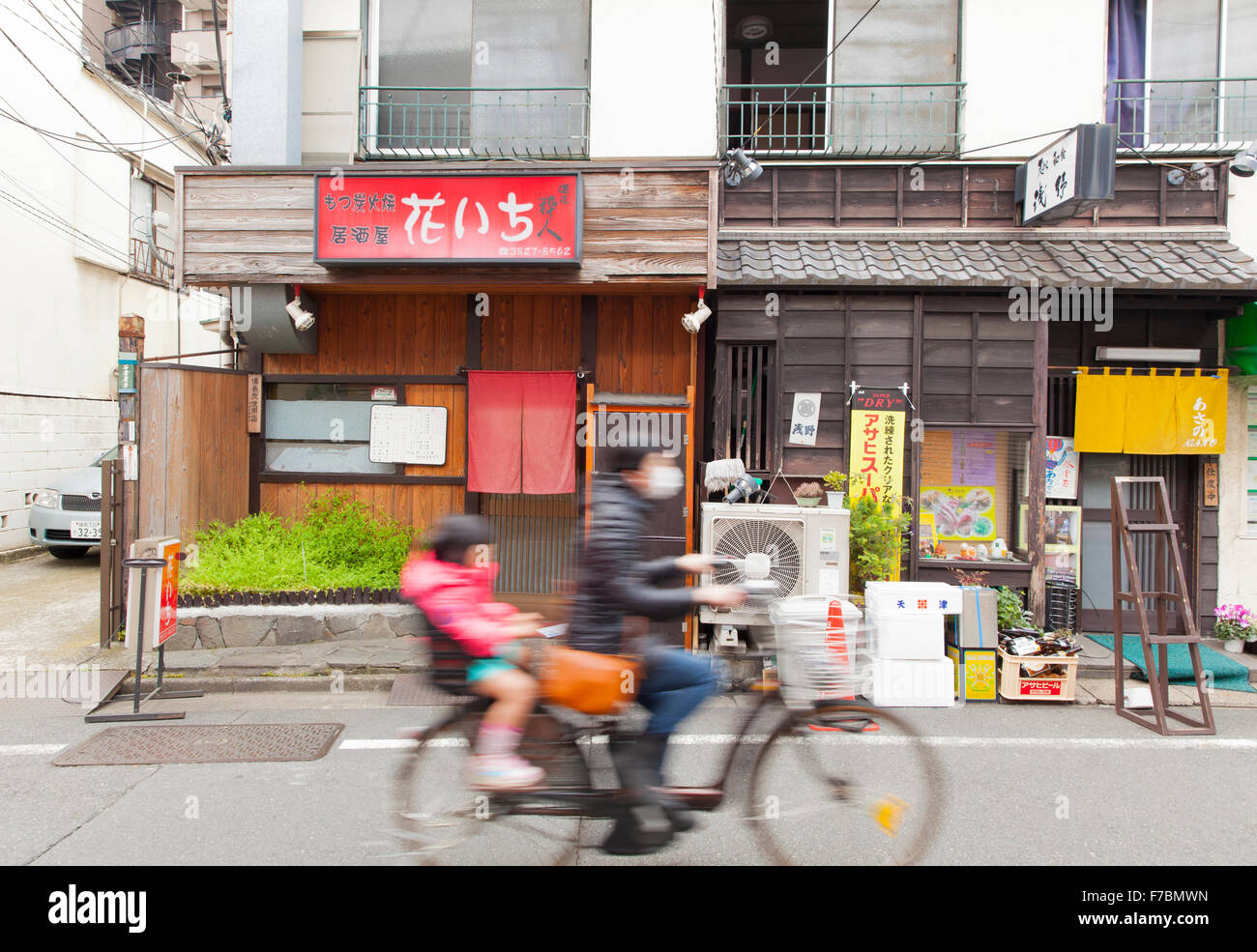 Un parent à vélo avec leur fille sur le siège arrière à Tokyo Banque D'Images