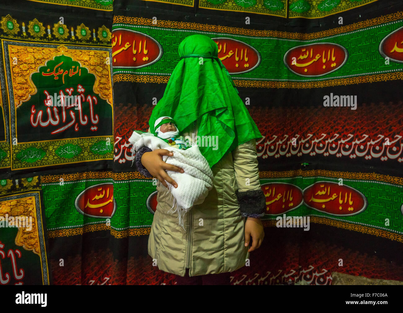 Femme iranienne avec Green voile couvrant son visage Holding A Baby Doll Au cours de Chehel Menbari Festival sur Tasua pour commémorer l'Imam Hussein, la province du Lorestan, Khorramabad, Iran Banque D'Images