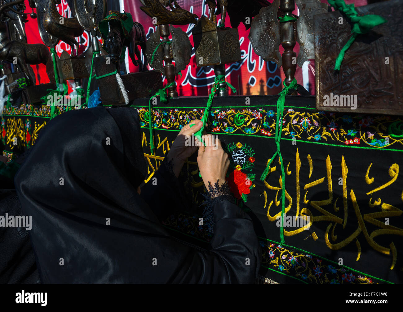 Les femmes chiites iraniens de mettre des rubans verts sur une Alam pour faire souhaits au cours de Chehel Menbari Festival le jour Tasua, la province du Lorestan, Khorramabad, Iran Banque D'Images