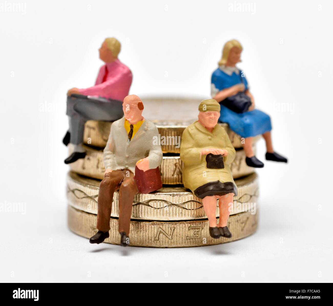 Les gens miniature assis sur une pile de pièces livre Banque D'Images