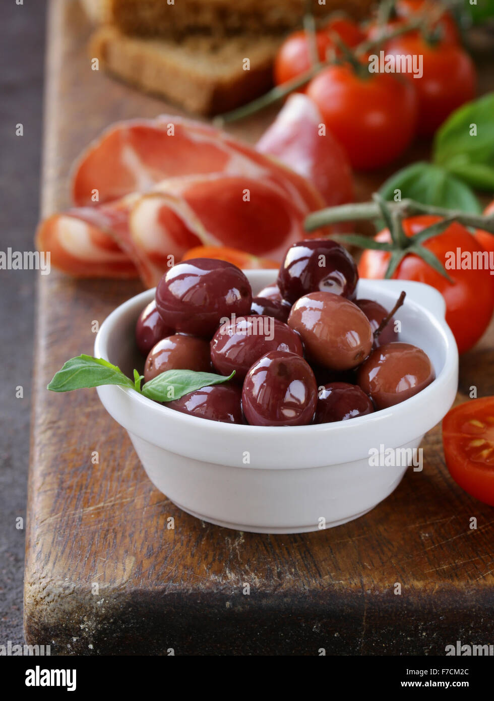 La nourriture italienne still life - olives, tomates, basilic, jambon prosciutto Banque D'Images