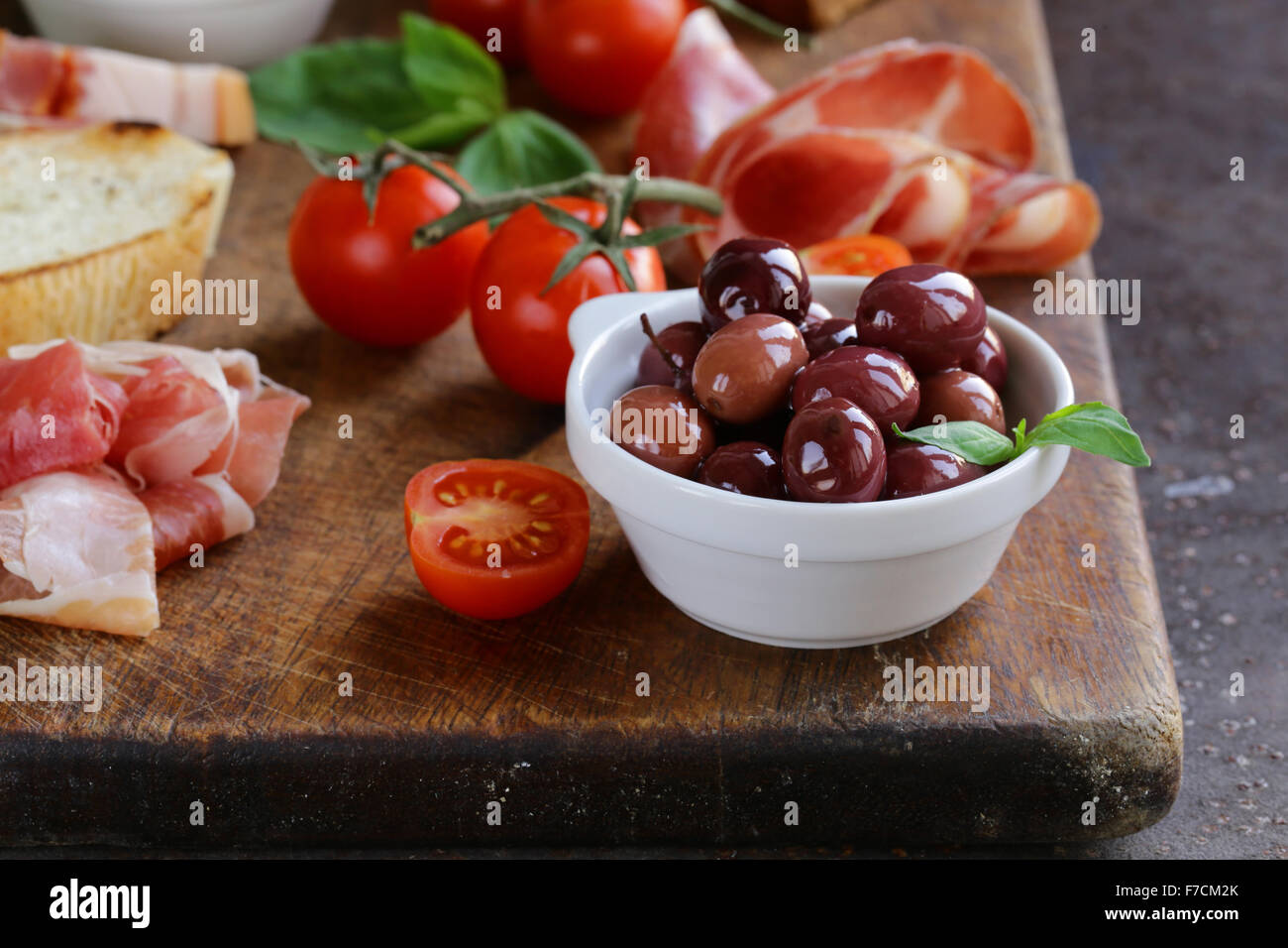 La nourriture italienne still life - olives, tomates, basilic, jambon prosciutto Banque D'Images