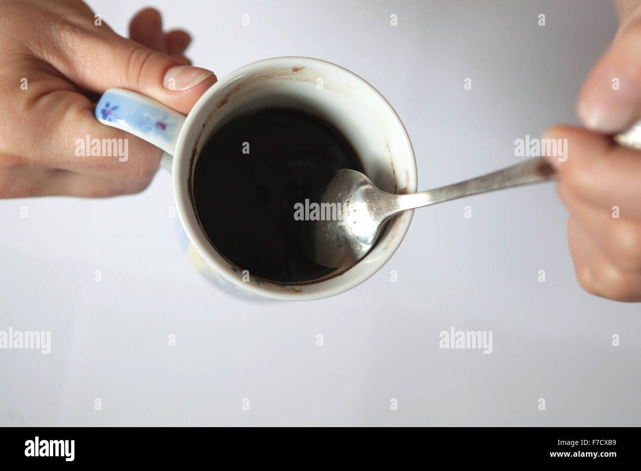 Une tasse de cuillère à café noir du matin dans les mains des femmes. Tasse à café vue du haut Banque D'Images