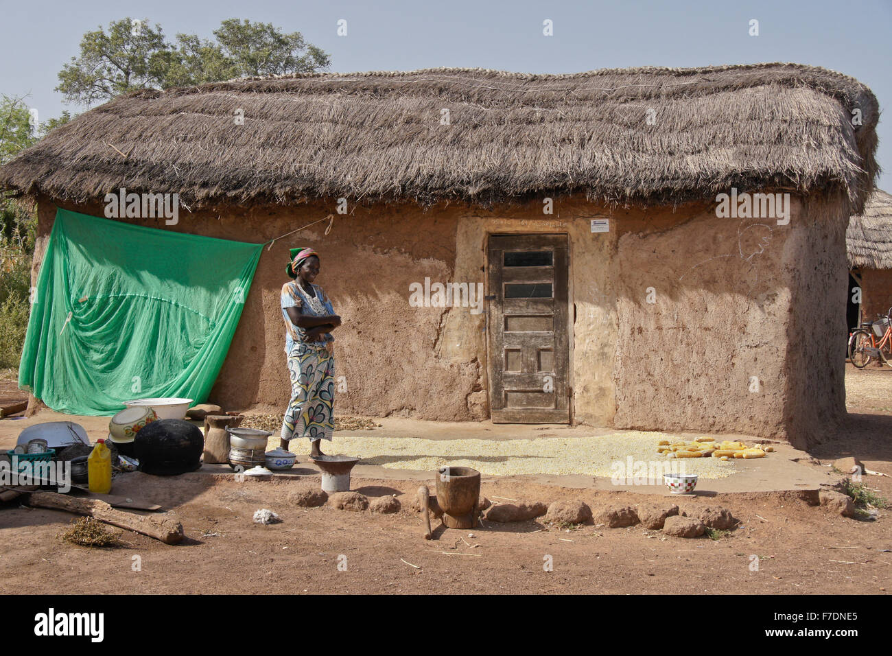 Séchage à l'extérieur de son maïs femme boue de chaume, maison Saakpuli, village du nord du Ghana Banque D'Images