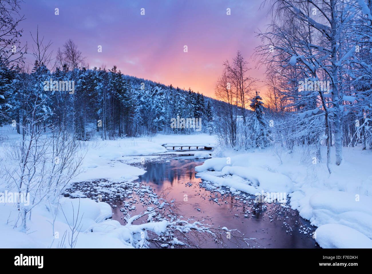 Une rivière gelée dans un paysage hivernal. Photographiée près de Levi en Laponie finlandaise au lever du soleil. Banque D'Images