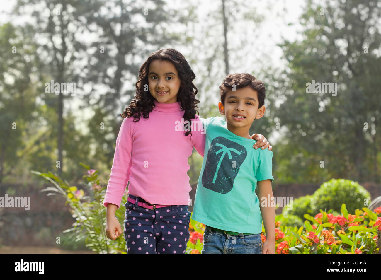 L'Inde, jeune garçon (4-5) et (6-7) debout avec les mains sur les épaules de jardin Banque D'Images