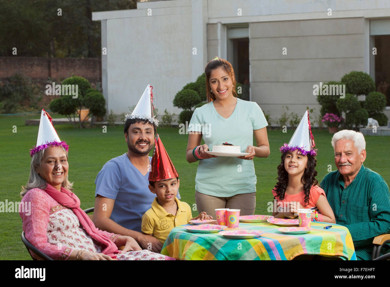 L'Inde, l'enfant (4-5, 6-7) avec les parents et grands-parents, assis à la table d'anniversaire sur l'arrière-cour Banque D'Images