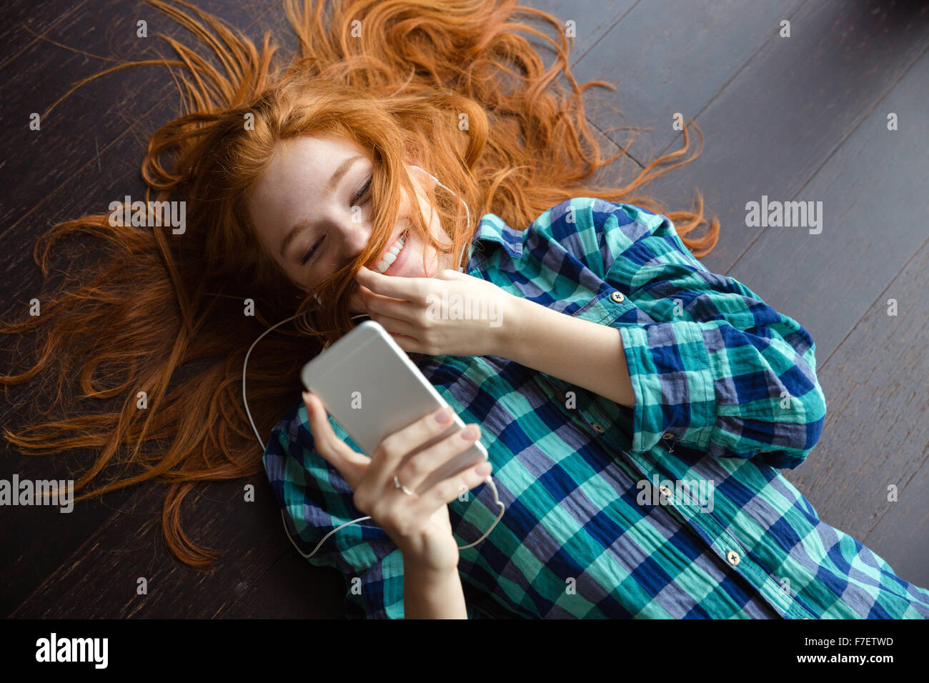 Amusant drôle fille rousse chemise à carreaux en jouant avec ses cheveux et écouter de la musique Banque D'Images