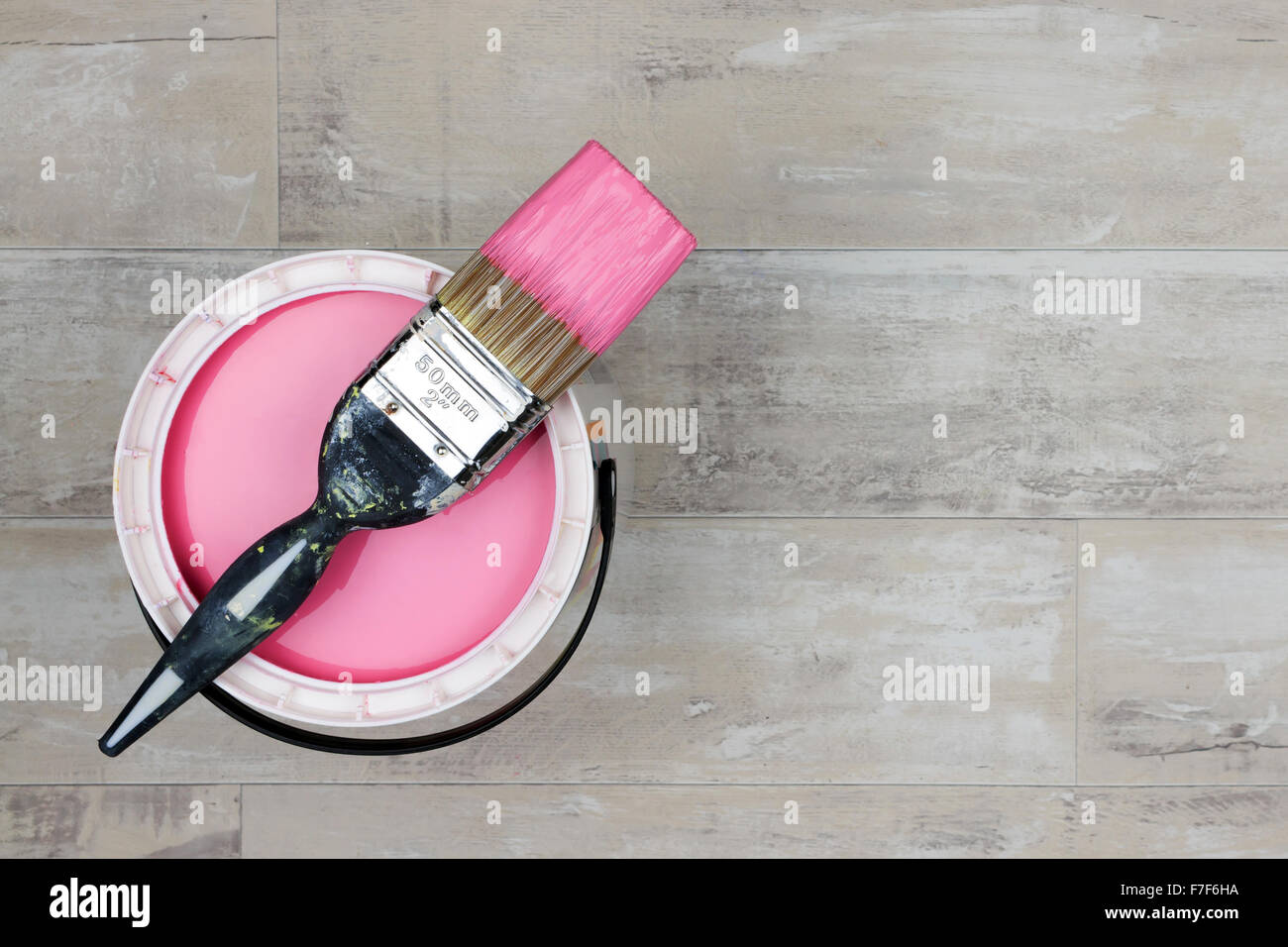 Regardant vers le bas sur un bidon de peinture rose avec paintbrush Banque D'Images