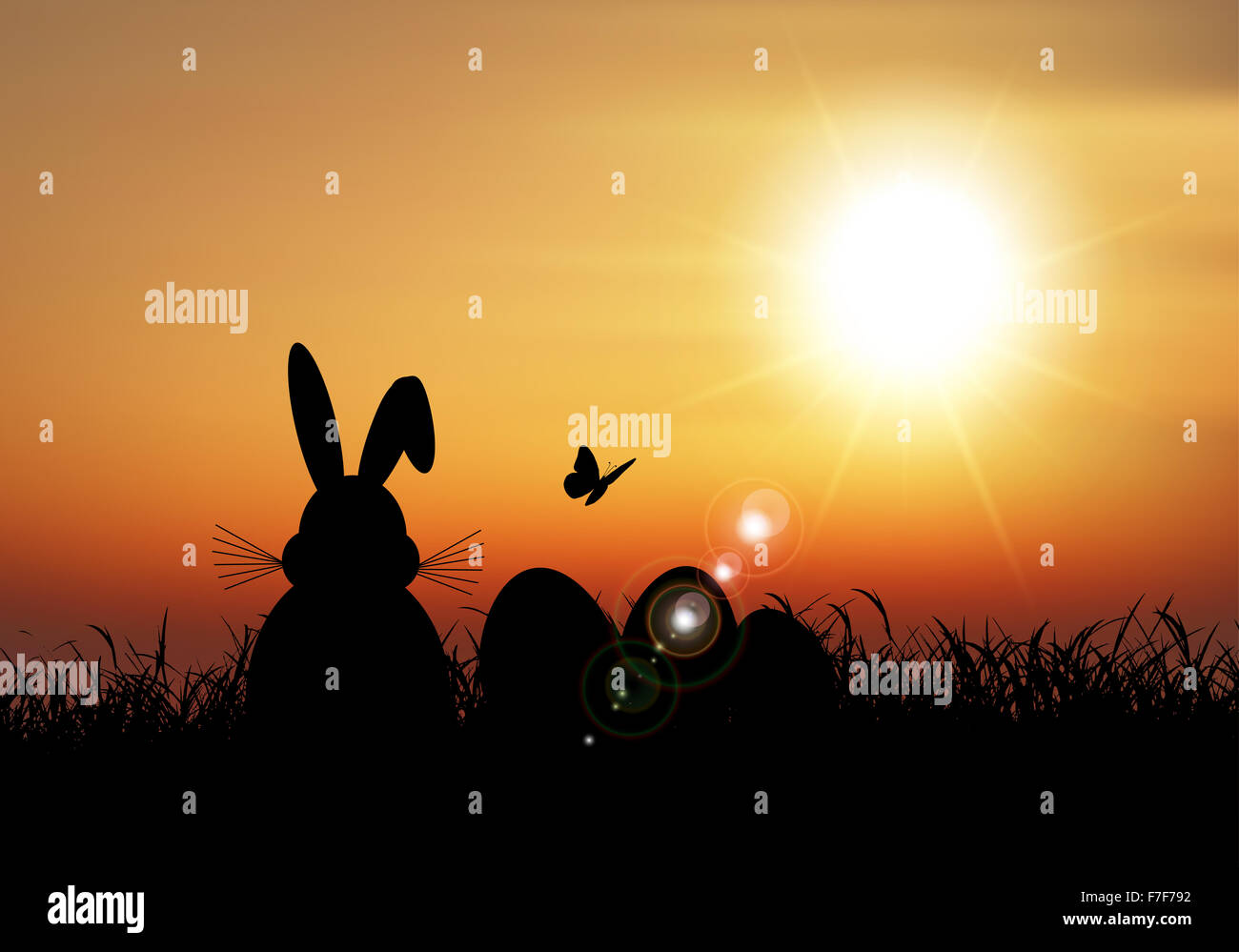 Silhouette de la lapin de Pâques assis dans l'herbe contre un ciel de coucher du soleil Banque D'Images