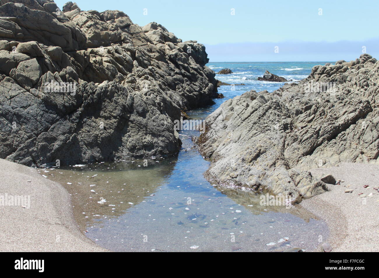 Piscine créé par les vagues venant à travers les rochers trois de quatre. Des petits cailloux et algues dans la piscine (trois sur quatre) Banque D'Images