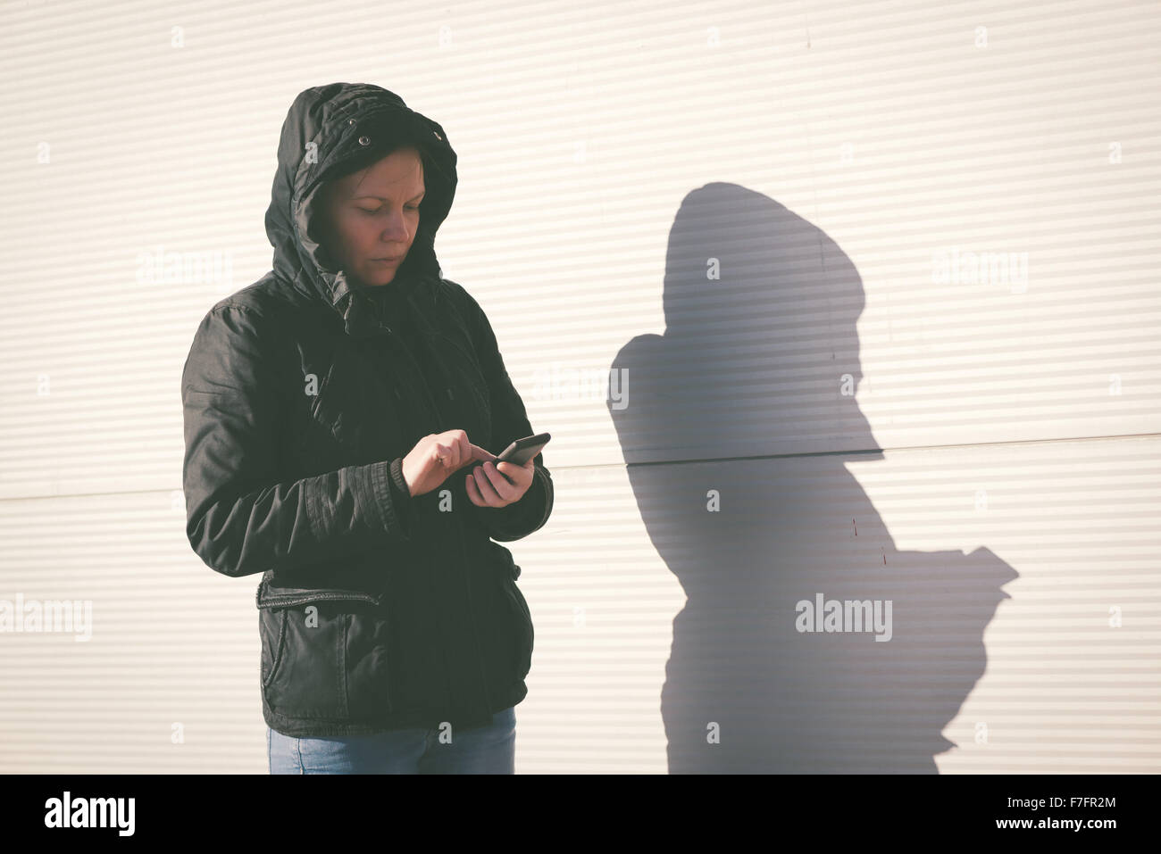 Femme textos SMS sur téléphone mobile, personne de sexe féminin dans la veste d'hiver à l'aide de l'extérieur, téléphone aux couleurs rétro droit Banque D'Images
