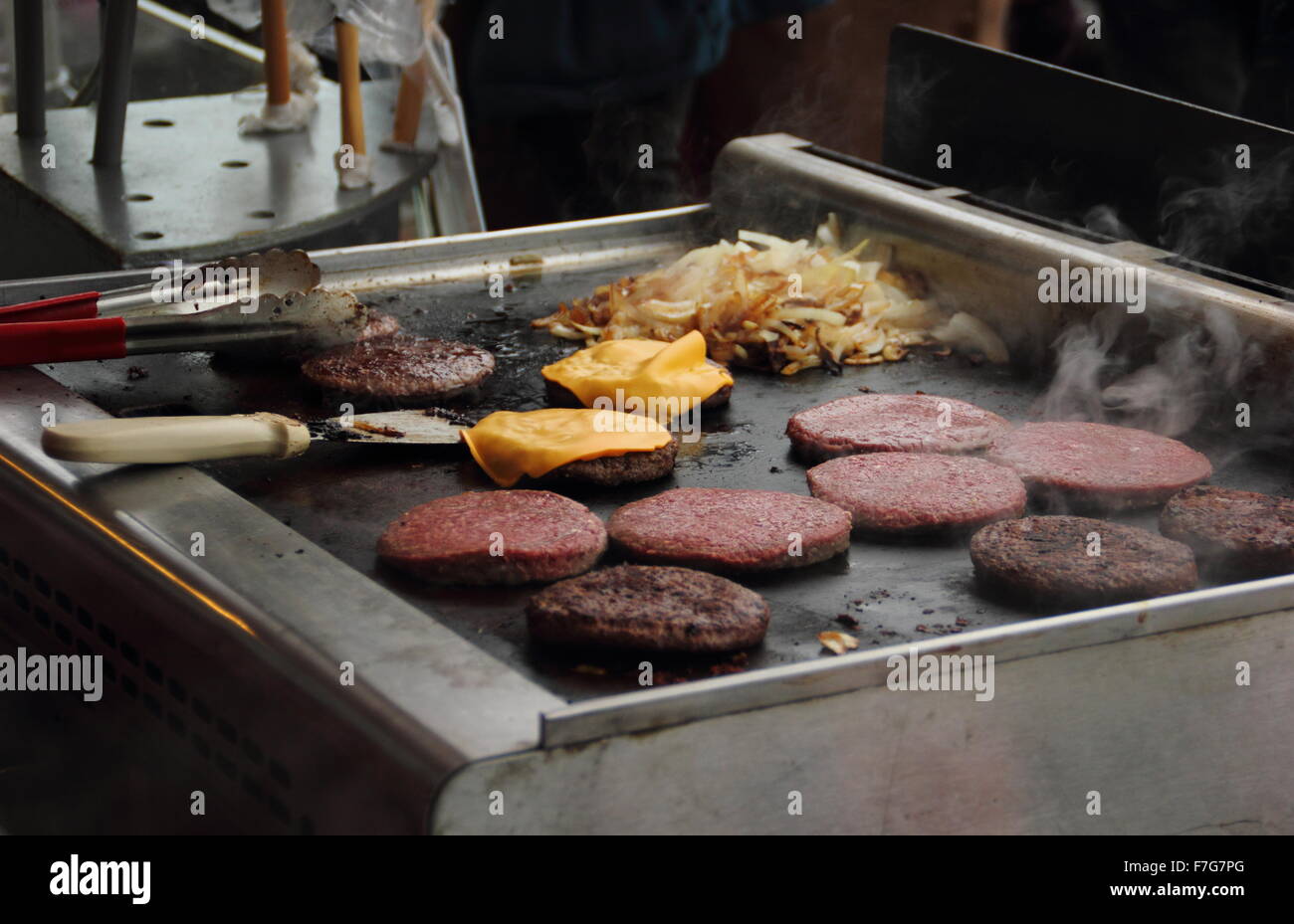 Les hamburgers et les oignons fry sur une cuisinière d'un décrochage de la nourriture à emporter à un marché de producteurs, Angleterre - 2015 Banque D'Images