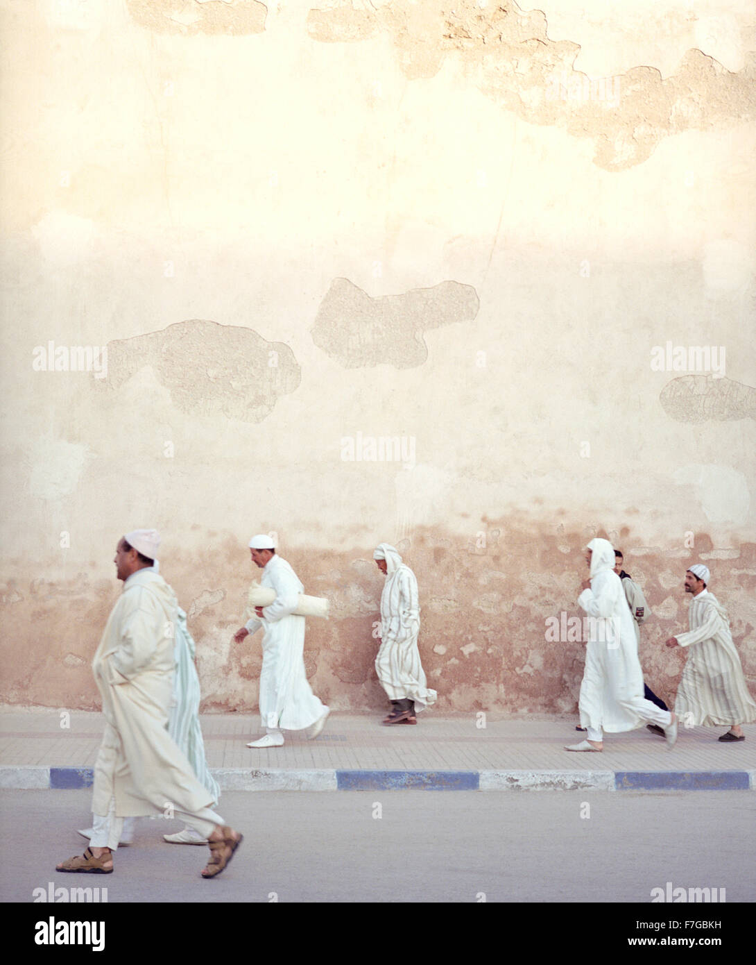 Les hommes musulmans marocains marcher rapidement passé les murs de la ville sur le chemin de la prière du matin. Essaouira, Maroc, Afrique du Nord. Banque D'Images