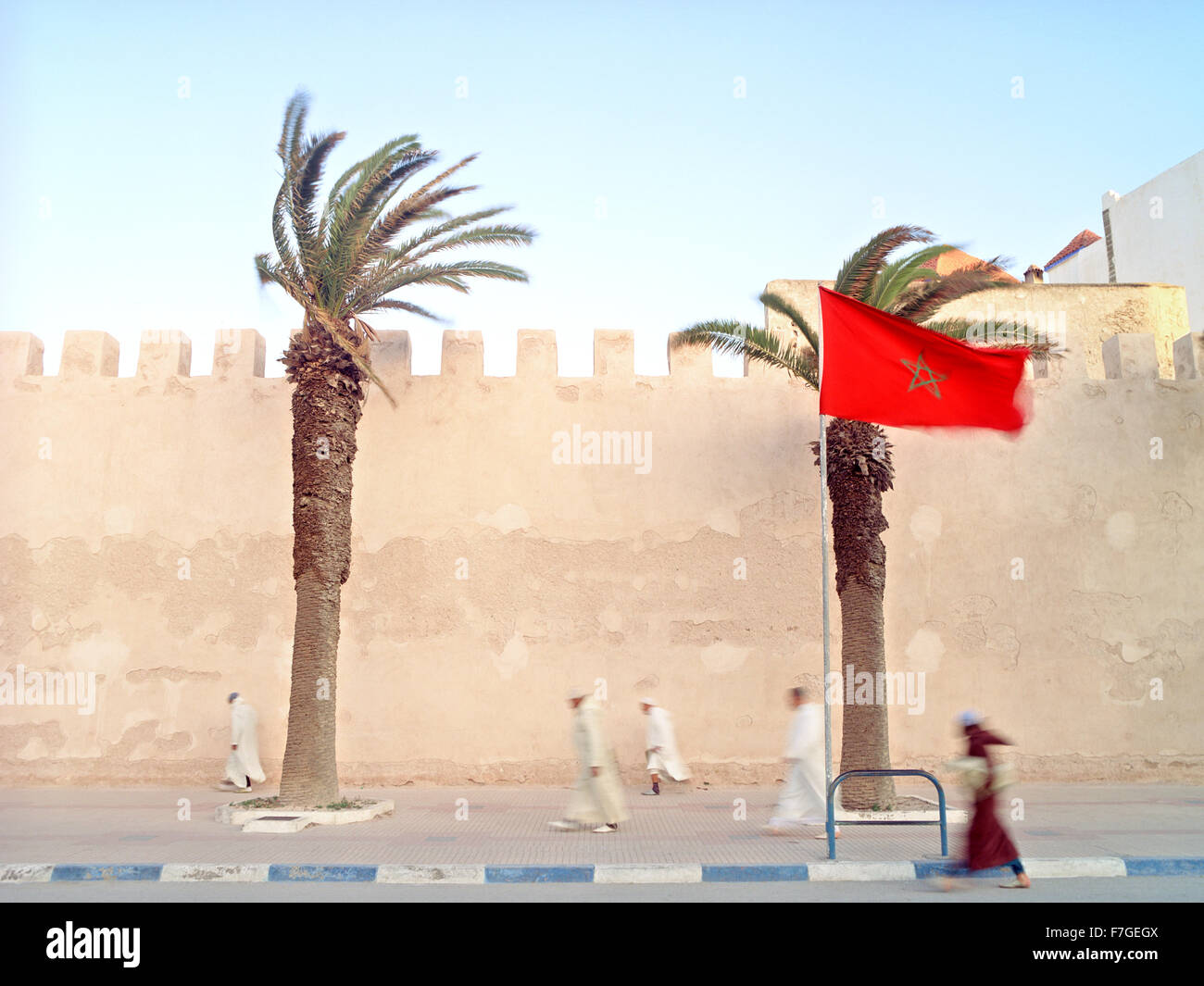 Les hommes musulmans marocains marcher rapidement passé les murs de la ville sur le chemin de la prière du matin. Banque D'Images