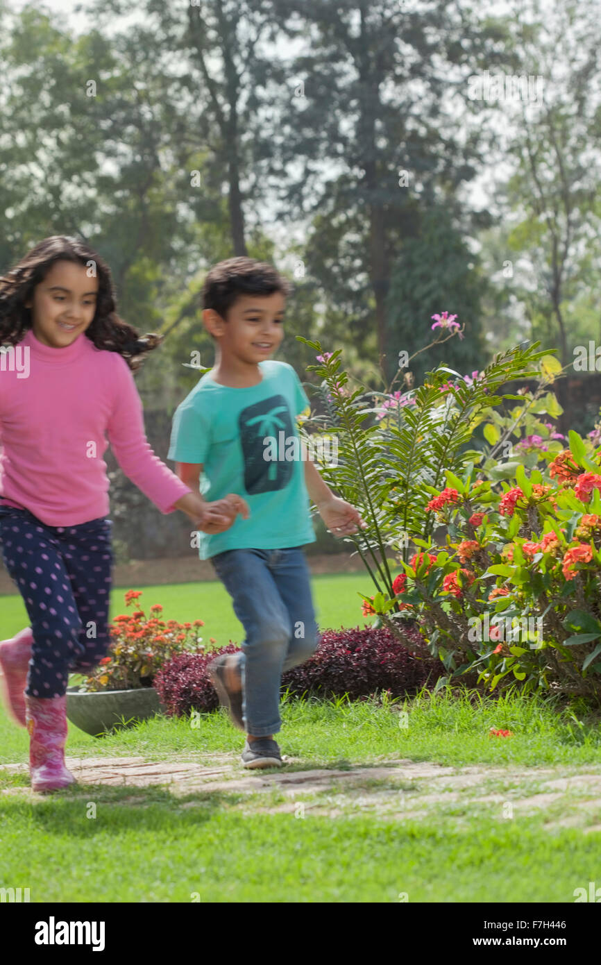 L'Inde, jeune garçon (4-5) et (6-7) s'exécutant dans jardin Banque D'Images