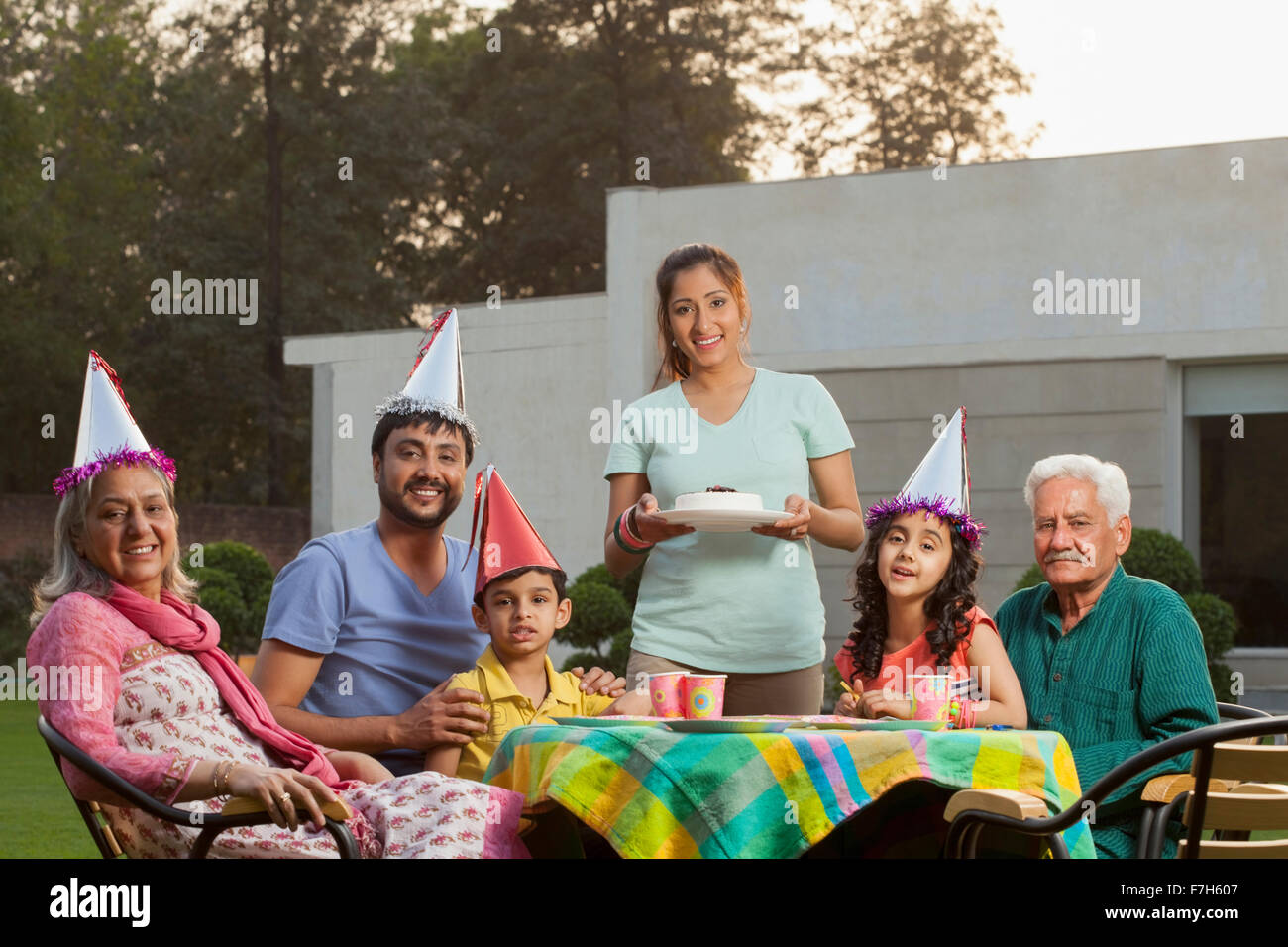 L'Inde, l'enfant (4-5, 6-7) avec les parents et grands-parents, assis à la table d'anniversaire sur l'arrière-cour Banque D'Images