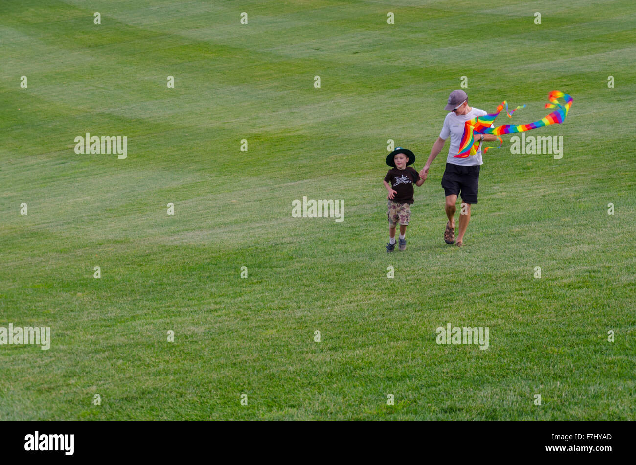 Un homme et son enfant marchant sur l'herbe à l'Arboretum national de Canberra, en Australie, avec un cerf-volant Banque D'Images