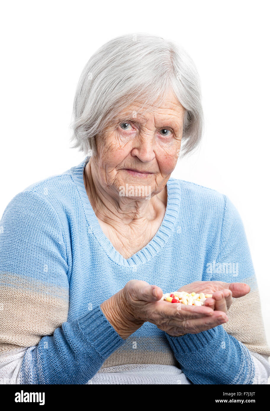 Femme âgée holding poignée de pilules prescrites over white Banque D'Images