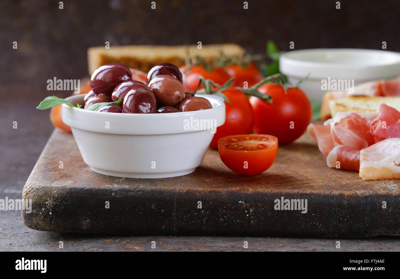 La nourriture italienne still life - olives, tomates, basilic, jambon prosciutto Banque D'Images