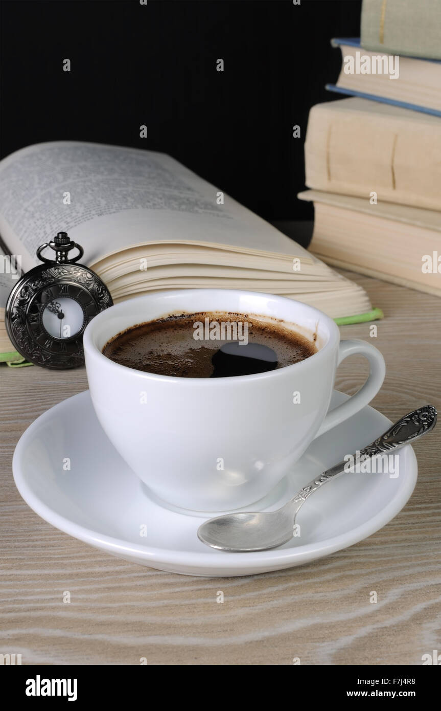 Fraîchement préparée et tasse de café parfumé sur une table entre books Banque D'Images