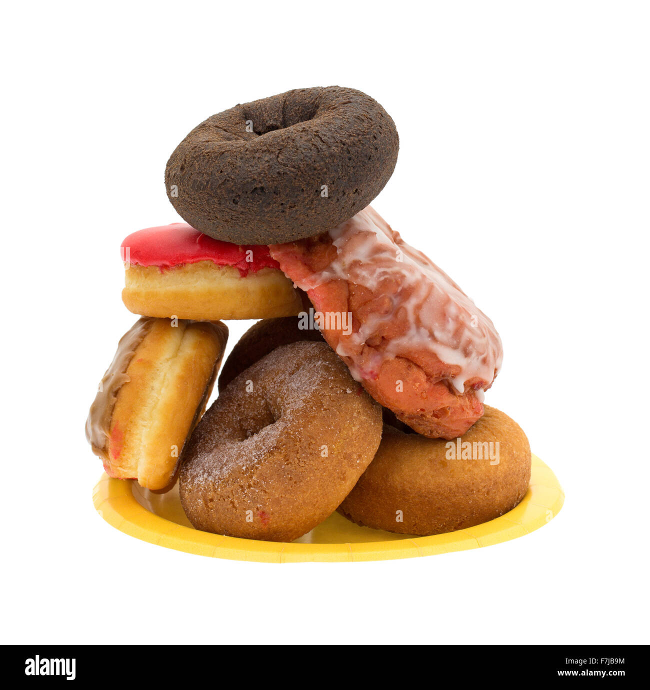 Une plaque de papier jaune avec une pile d'un assortiment de donuts et beignets de cerises glacées sur un fond blanc. Banque D'Images