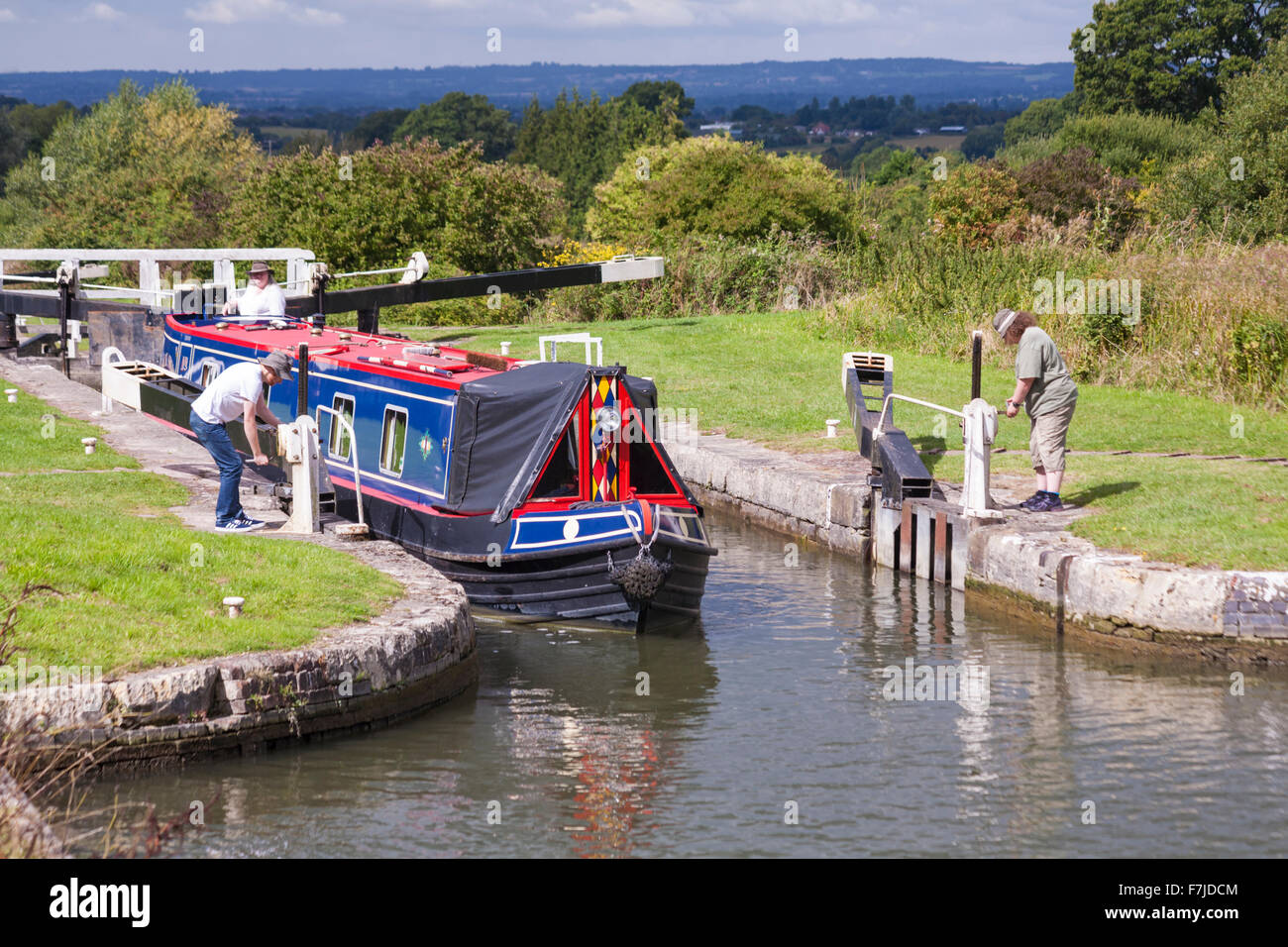 Femme à la direction de Black Swan Narrow boat à travers les portes d'écluse sur le canal Kennet et Avon, Devozes, Wiltshire, Angleterre, Royaume-Uni en août Banque D'Images