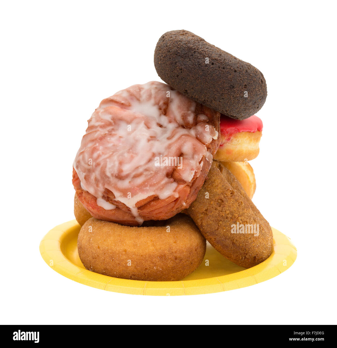 Une plaque de papier jaune avec une pile d'un assortiment de donuts et beignets de cerises glacées sur un fond blanc. Banque D'Images