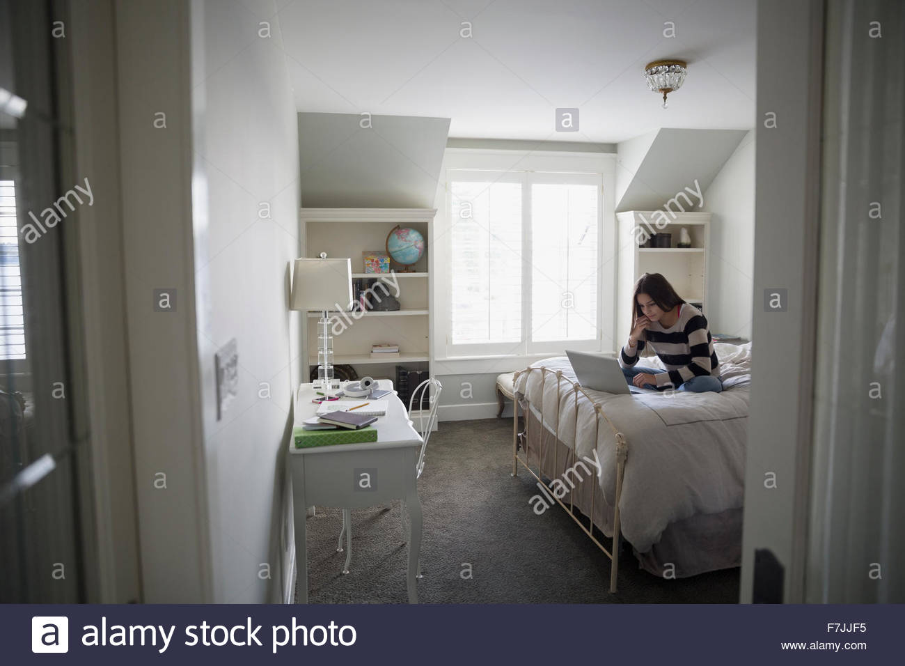 Teenage girl using laptop on bed Banque D'Images