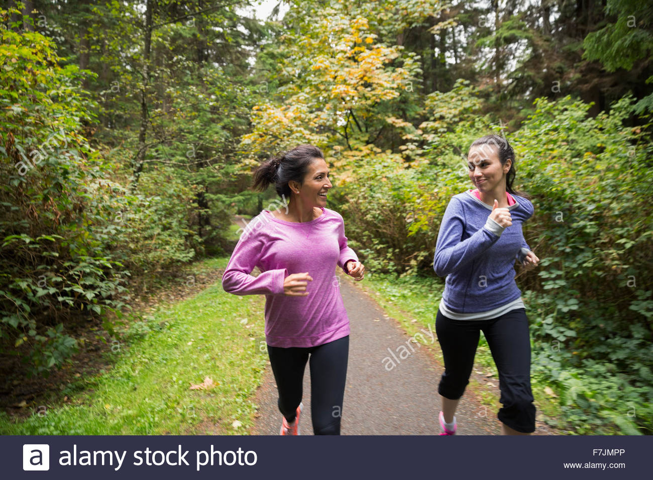 Mère et fille jogging le chemin dans les bois Banque D'Images