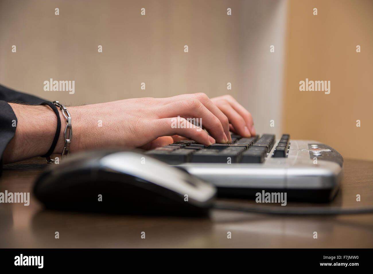 Main d'un homme travaillant à l'ordinateur en train de taper au clavier dans son bureau, sur le desktop Banque D'Images