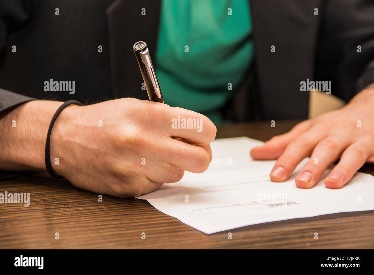 Les mains de l'homme assis dans un bureau de travail la signature d'une feuille de papier ou un document avec un stylo, sur le desktop Banque D'Images
