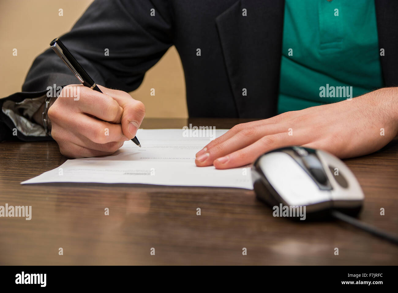 Les mains de l'homme assis dans un bureau de travail la signature d'une feuille de papier ou un document avec un stylo, sur le desktop Banque D'Images