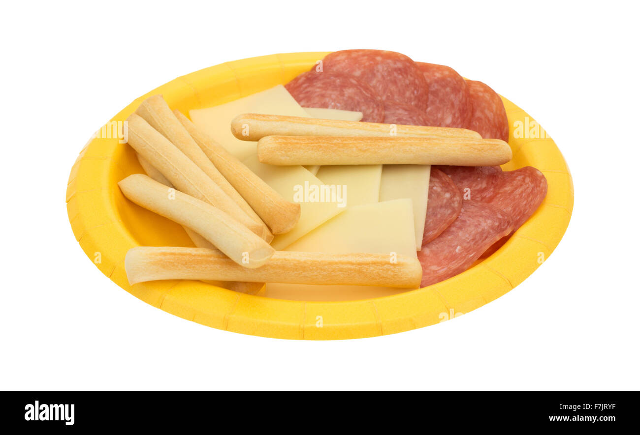 Une plaque de papier jaune avec des tranches de salami de Gênes et de fromage provolone gressins plus isolé sur un fond blanc. Banque D'Images