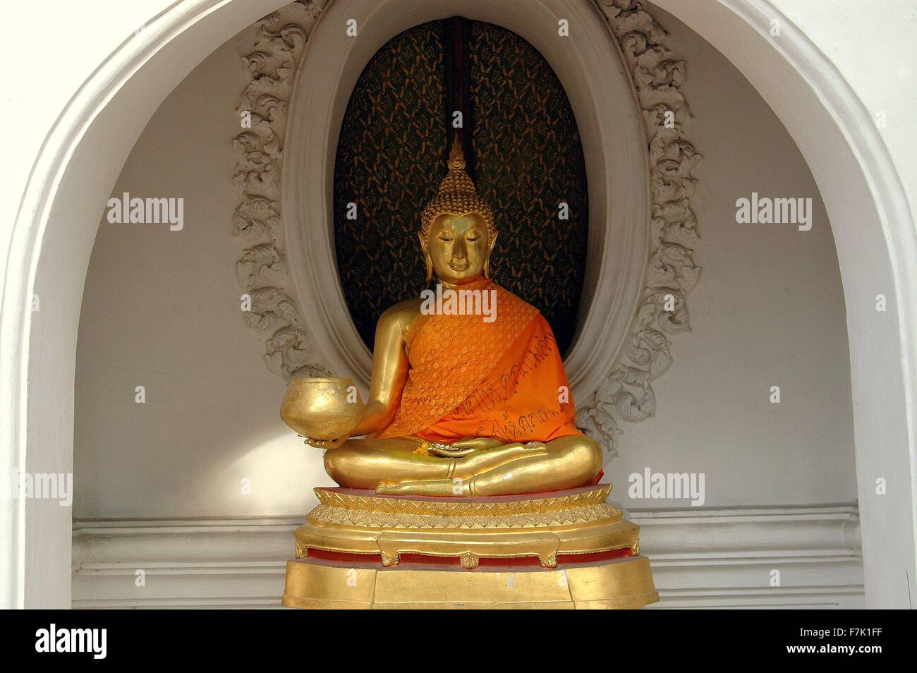 Nakhn Pathom, Thaïlande : dorées de Bouddha assis, drapé d'une écharpe orange dans une niche à arcades du Wat Phra Pathom Chedi Banque D'Images