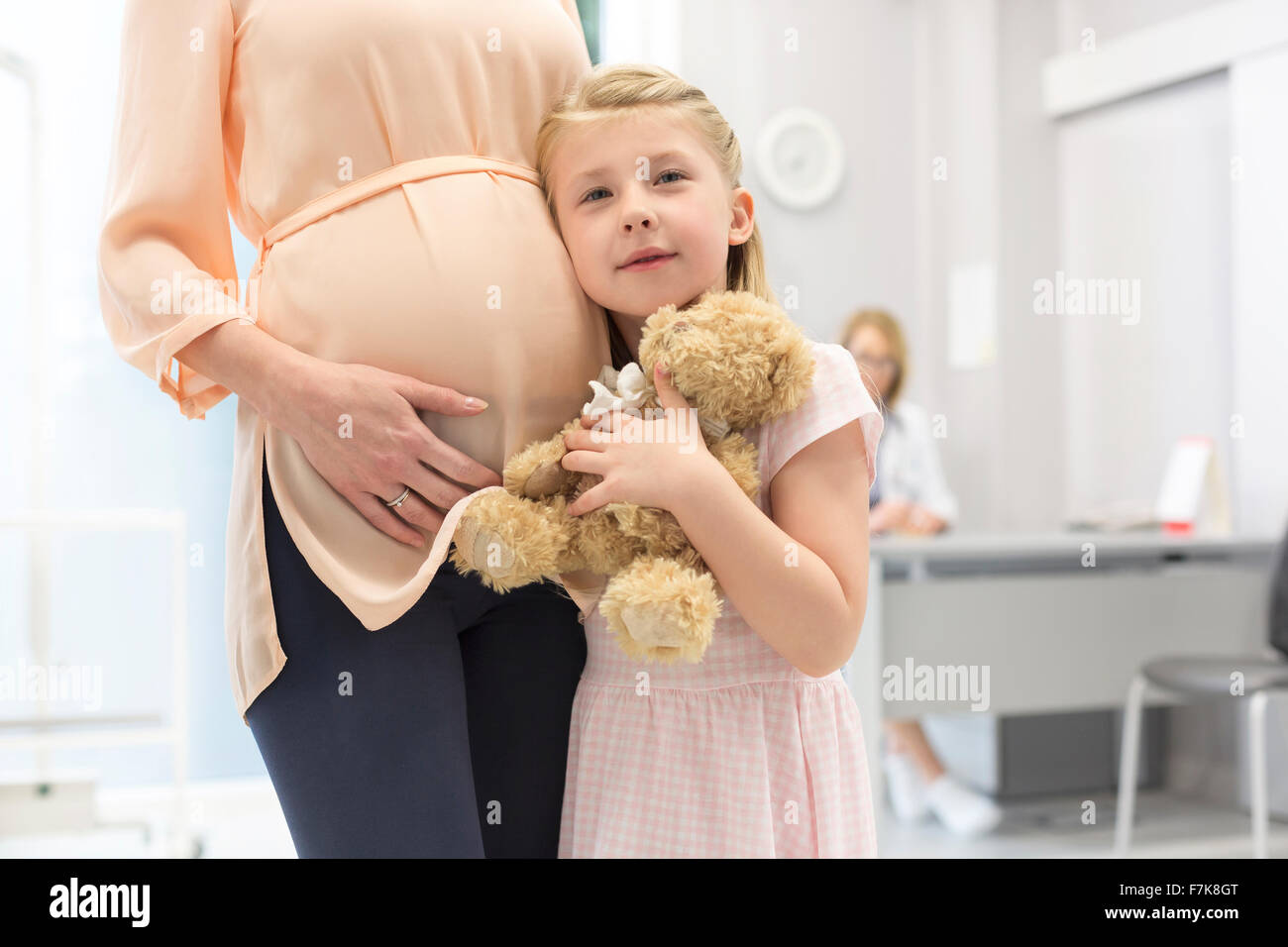 Portrait girl hugging teddy bear avec mère enceinte dans le cabinet du médecin Banque D'Images