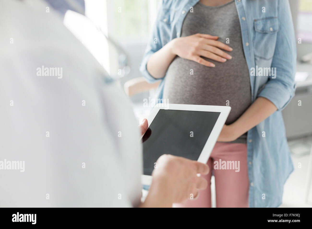 Médecin avec tablette numérique de parler à la patiente enceinte Banque D'Images