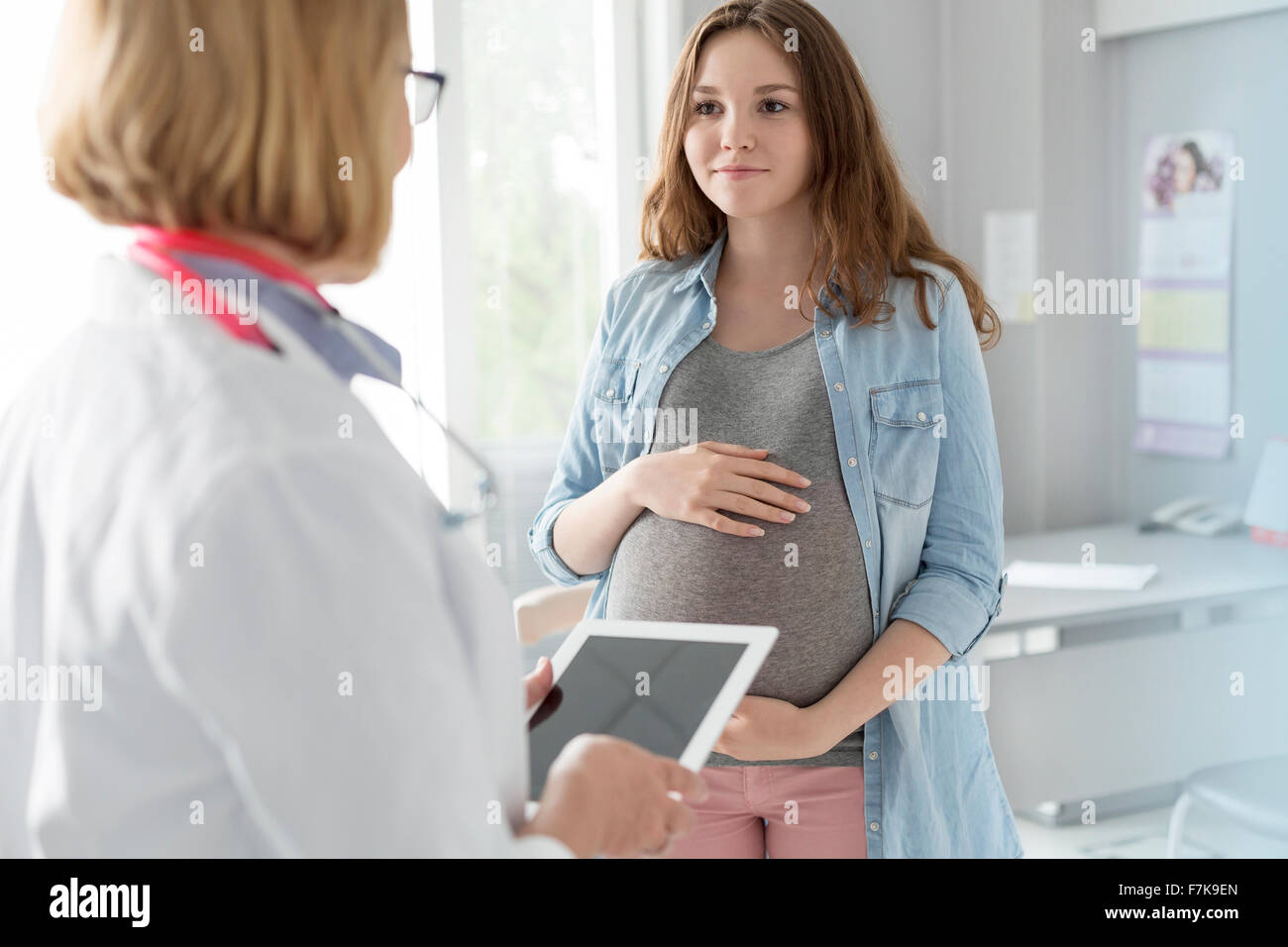 Médecin avec tablette numérique de parler avec les femmes enceintes et les patients en salle d'examen Banque D'Images