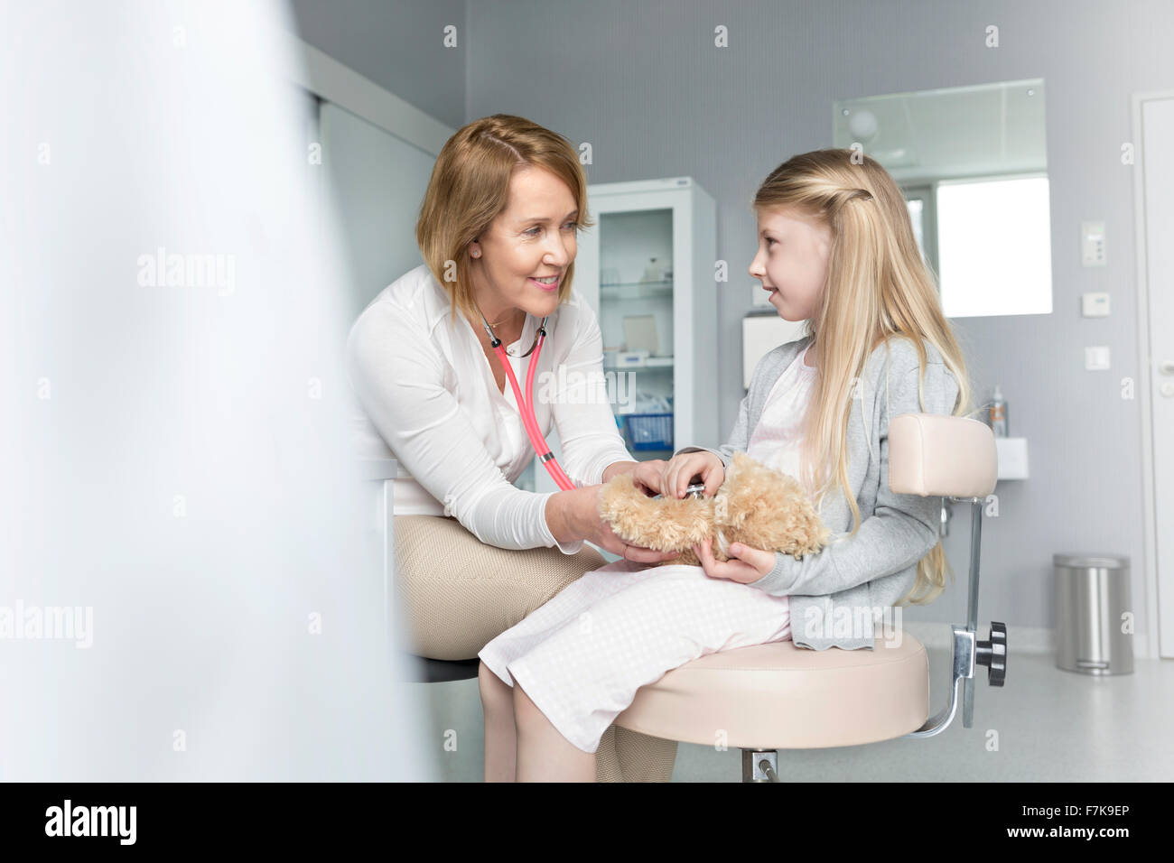 À l'aide d'un pédiatre sur fille stéthoscope ours du patient en salle d'examen Banque D'Images