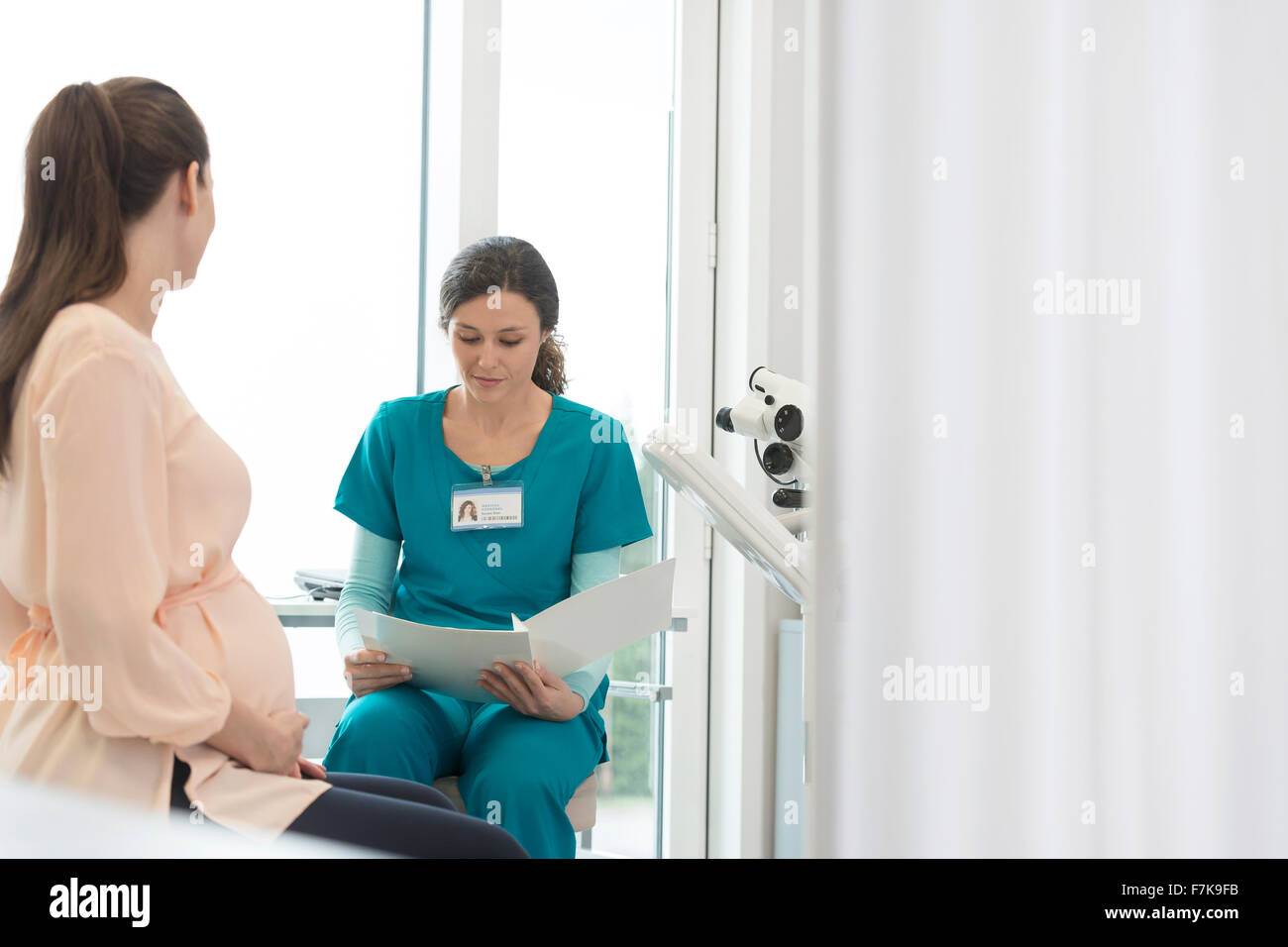 Infirmière et patiente enceinte l'examen medical chart in examination room Banque D'Images