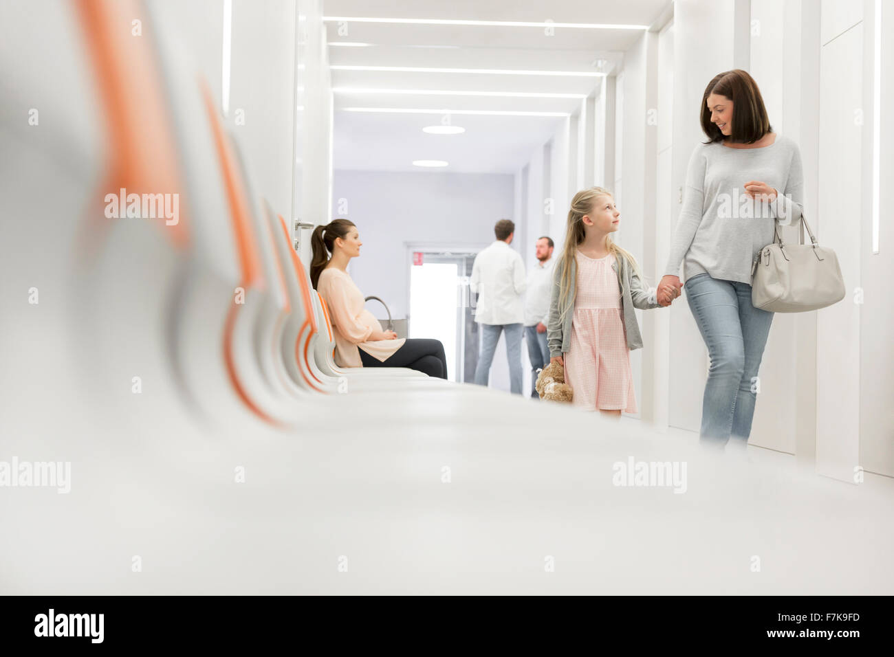 Mother and Daughter holding hands walking in hospital corridor Banque D'Images