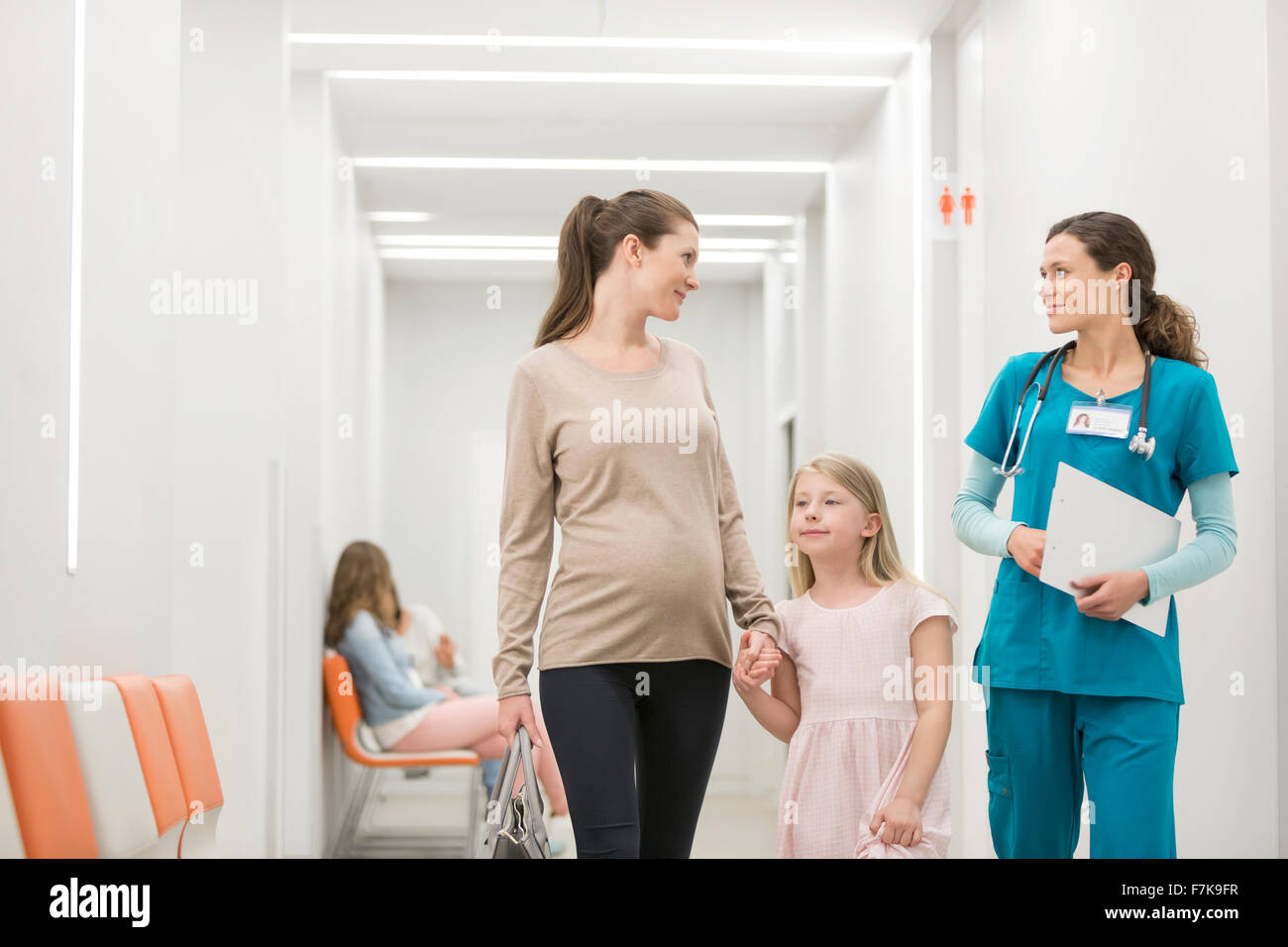 Nurse talking to mother and daughter in hospital corridor Banque D'Images