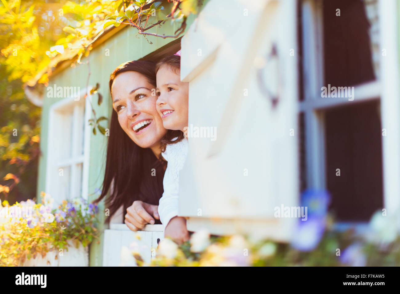 Smiling mother and daughter dans fenêtre playhouse Banque D'Images