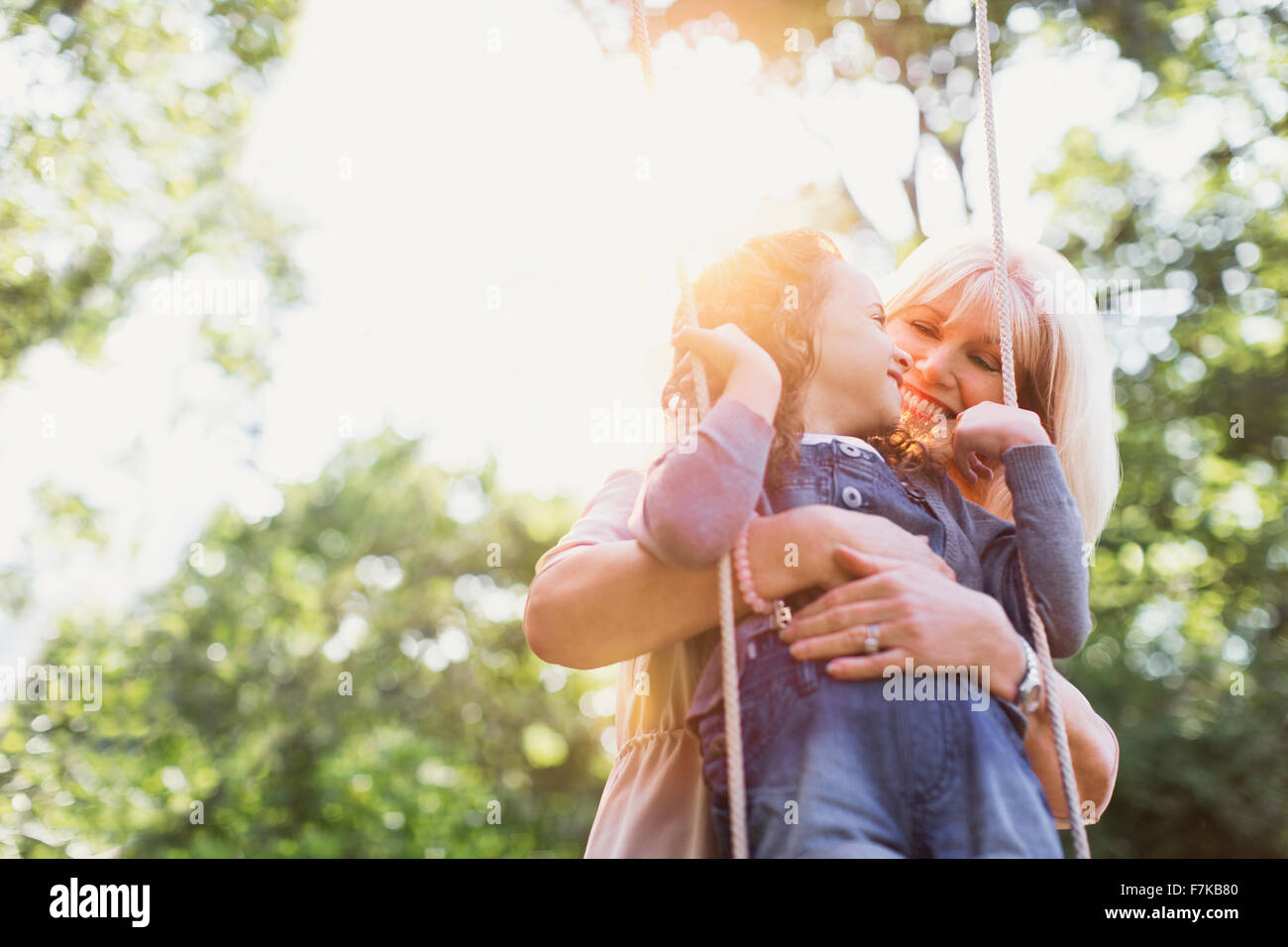 Grand-mère hugging granddaughter on swing Banque D'Images