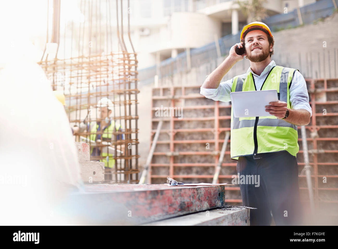 Engineer with digital tablet talking on cell phone at construction site Banque D'Images