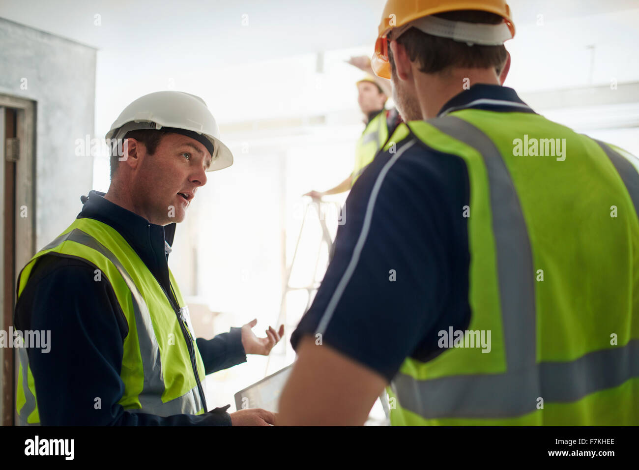 Travailleur de la construction et ingénieur with digital tablet talking at construction site Banque D'Images